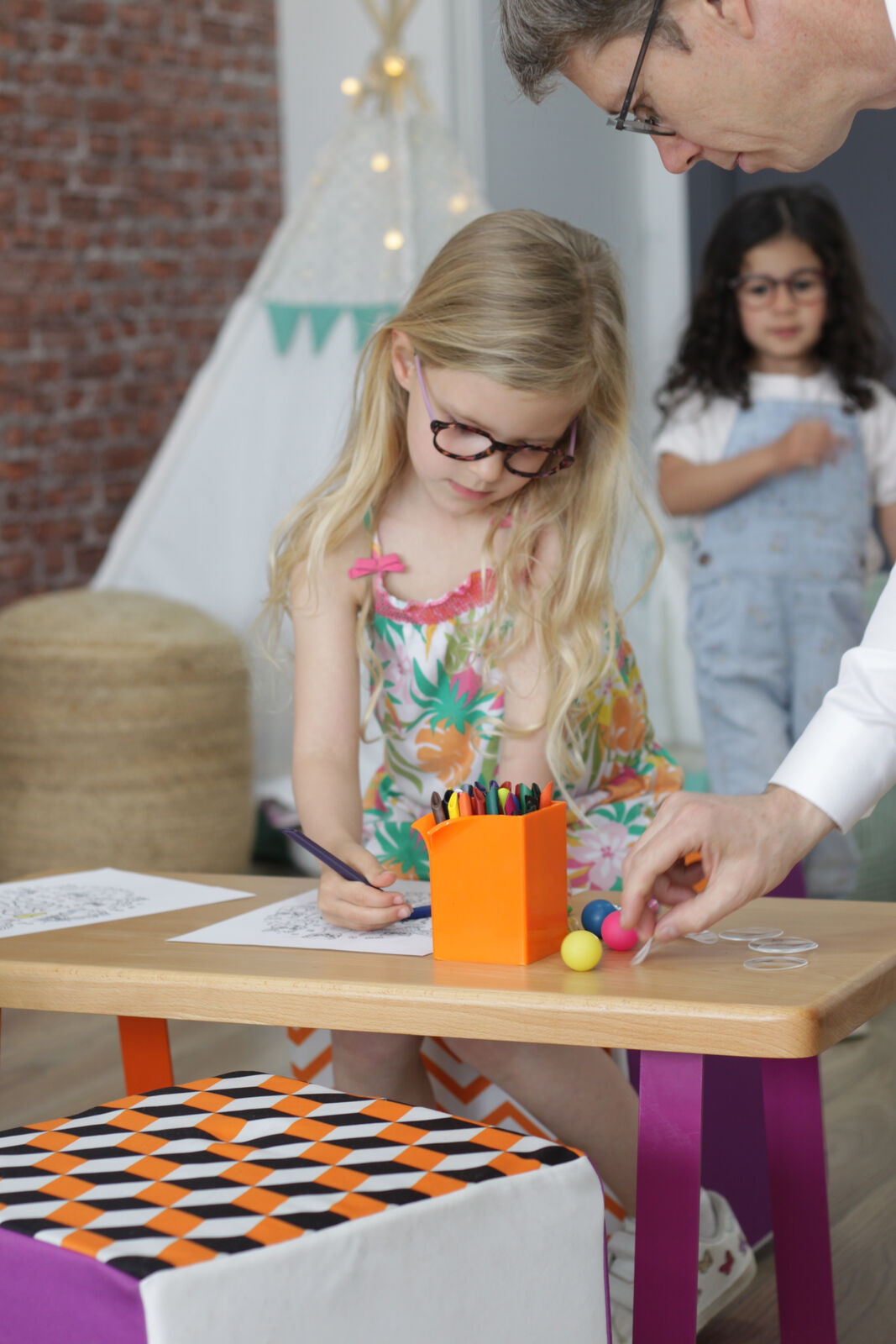 Une enfant dessine avec des crayons de couleur dans l'espace enfants de MAHU Opticien à Manduel